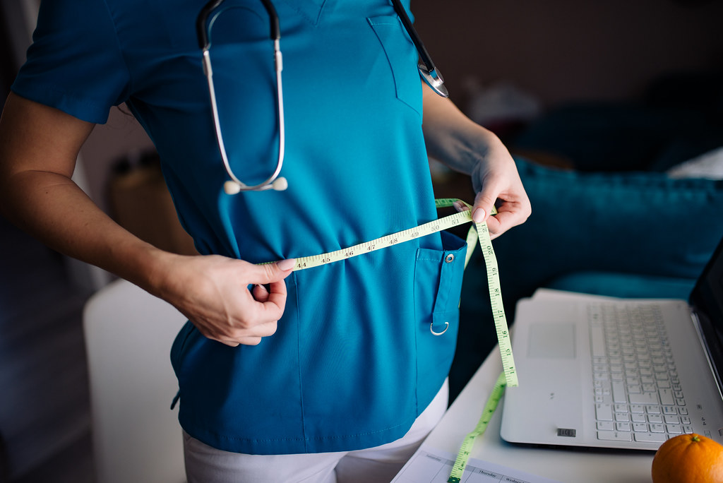 A healthcare professional measures waist circumference with a tape measure